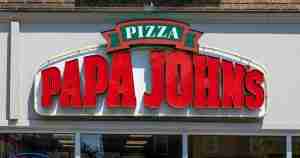 Papa John's pizza shop sign with large red logo and a green 'PIZZA' banner above the storefront.