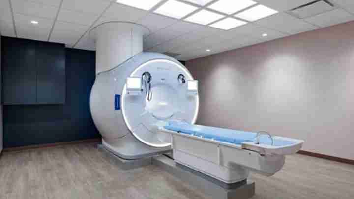 MRI scanner with patient table extended, in a clinical room ready for imaging.
